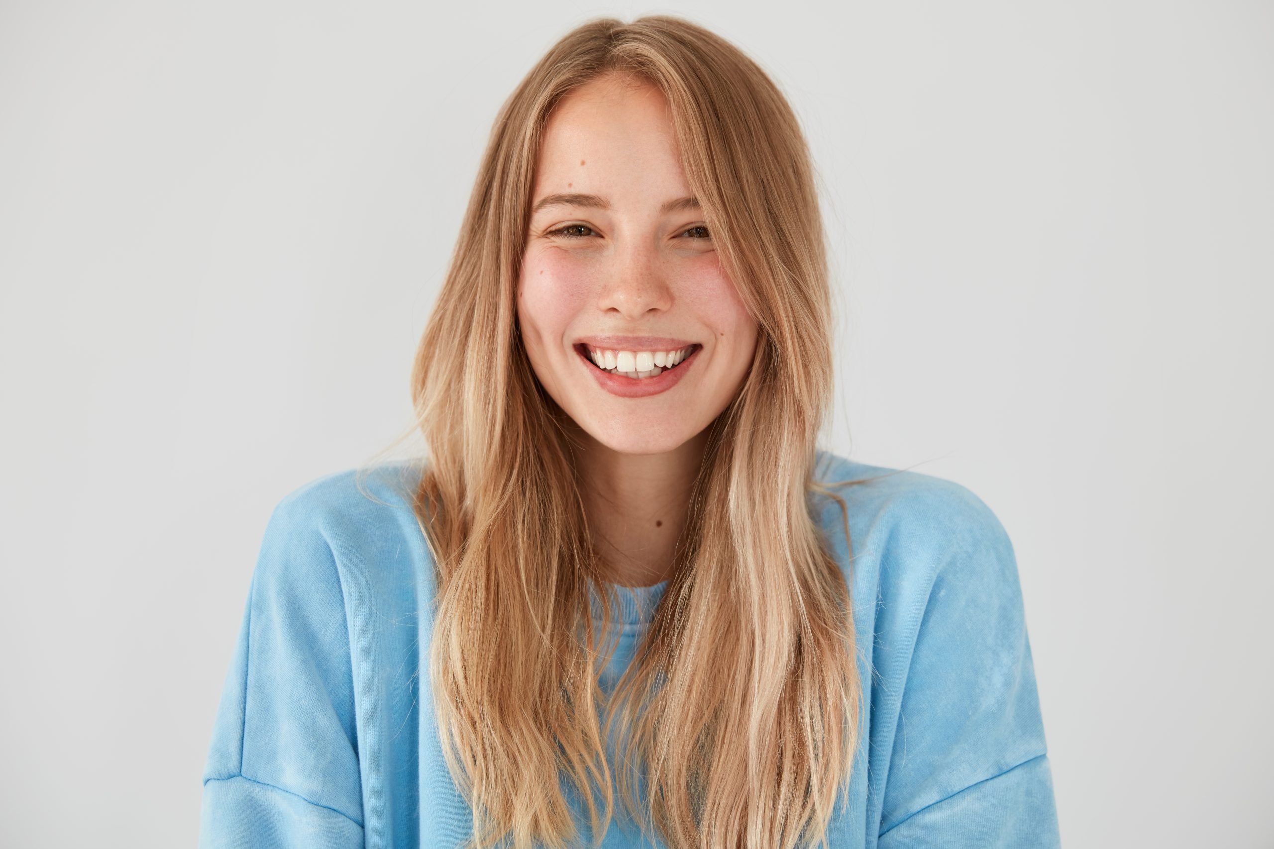 Optimistic lovely woman with charming sincere smile, being in good mood, rejoices starting new stage in life after getting married, wears casual outfit poses against white background. People, emotions